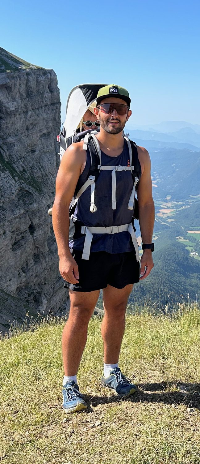 Antoine en randonnée en montagne avec un enfant dans un porte-bébé